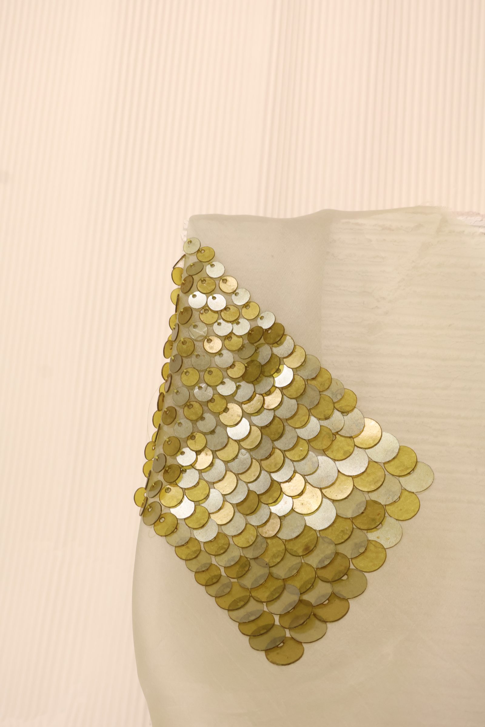 A diamond panel of gold and silver scale sequins stitched onto sheer fabric, catching the light