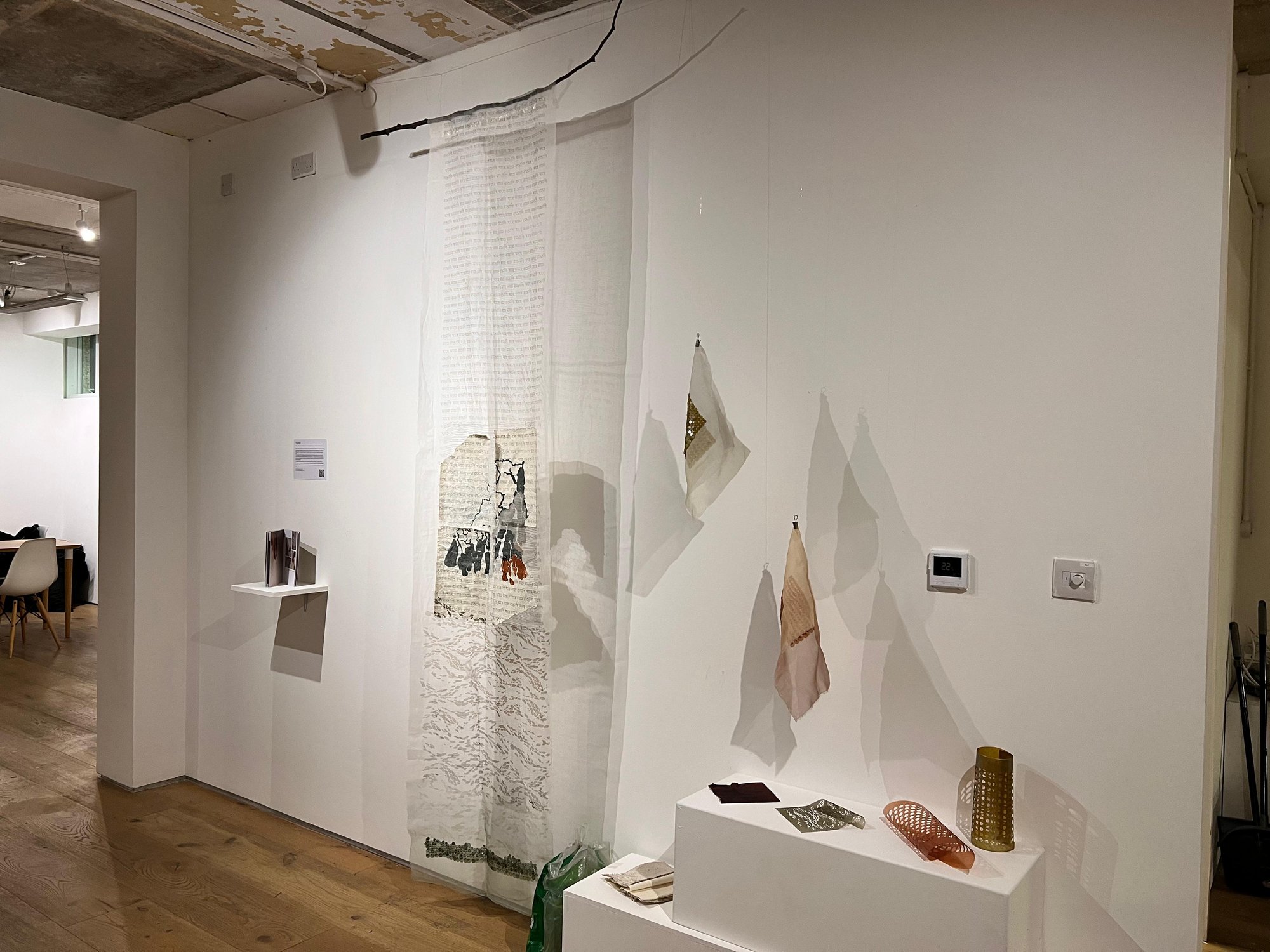 Wide installation view at (RE)MATERIALISED, hanging sequin and textile pieces on a gallery wall